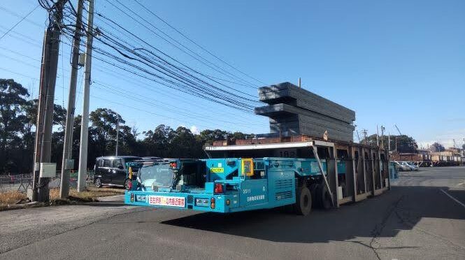 A heavy-duty transporter loaded with pallets and steel plates