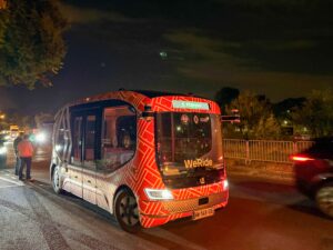 WeRide and Renault: Robobus driving on the road in the dark, surrounded by traffic. 