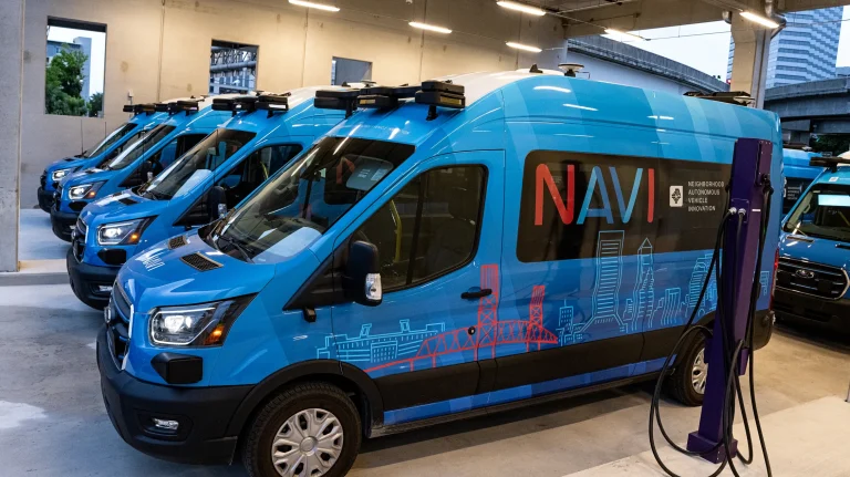 Beep begins operating fully autonomous public transit system NAVI in Florida Ford E-Transit vehicles integrated with Oxa's automated driving system (ADS) shown here parked indoors in a line.