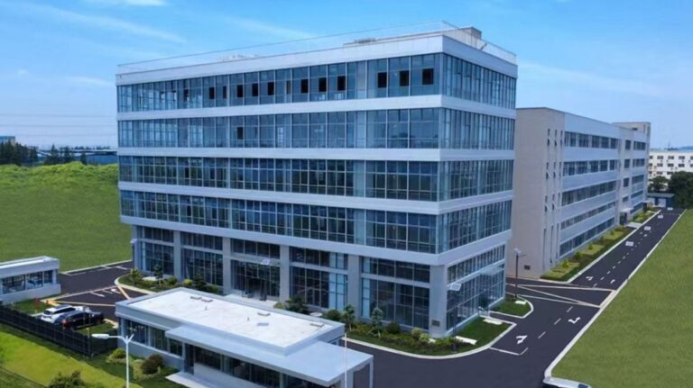 An aerial photo of the Valeo manufacturing facility in Waigang Industrial Park in China, with a round along two sides of the building and green grass alongside this