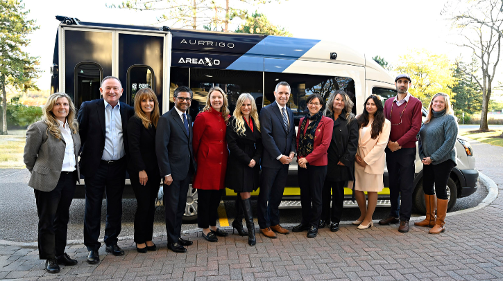 Aurrigo debuts winter-ready autonomous shuttle in Canada Kanata North shuttle launch attendees standing in front of the winter-ready Level 4 autonomous shuttle in Ottowa