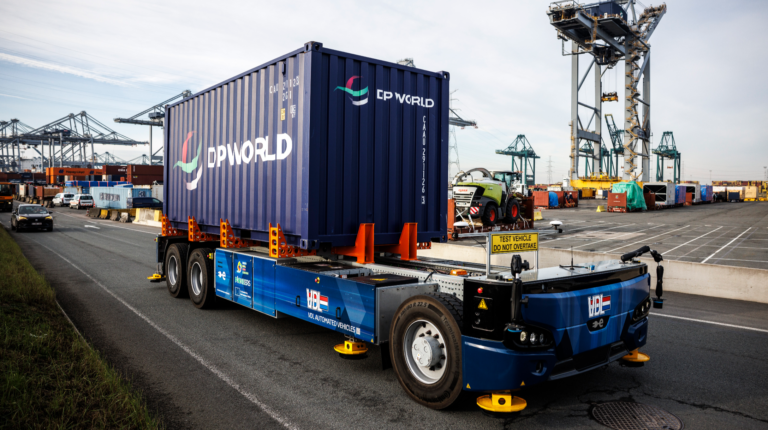 A container is transported by a low-rise, blue autonomous vehicle at DP World's Antwerp Terminal.