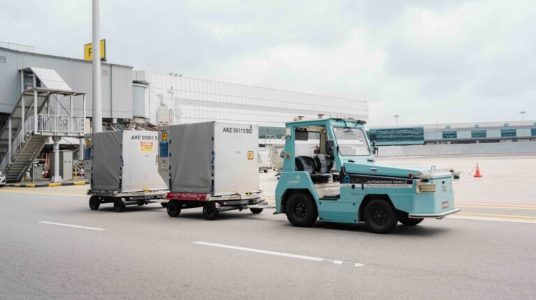 A turquoise driverless tractor deployed airside at Changi Airport.