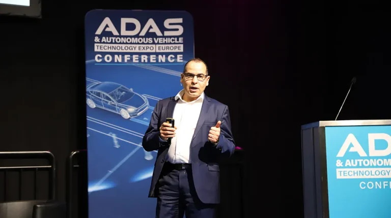 Benazouz Bradai, the research and innovation director and master expert in ADAS/autonomous driving at Valeo, pictured on stage at the 2025 Autonomous Vehicle Technology Conference. He is wearing a white a shirt and a dark suit.