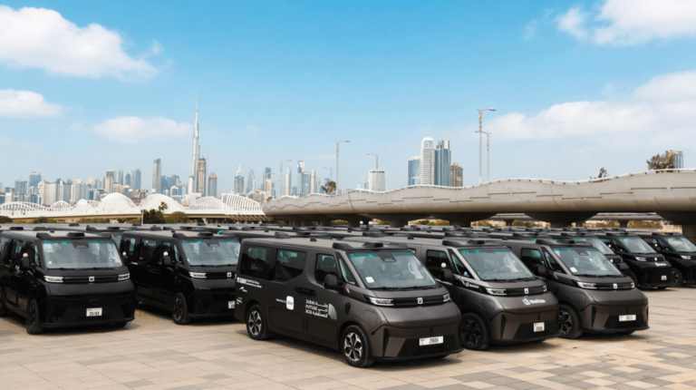 A fleet of parked black driverless robotaxis in Dubai, with the city skyline in the background.