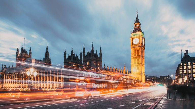 Blurred lights of vehicles crossing Westminster Bridge in London with the Houses of Parliament in the background.