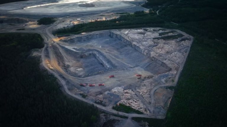Aerial view of a quarry with five Volvo autonomous trucks in operation.